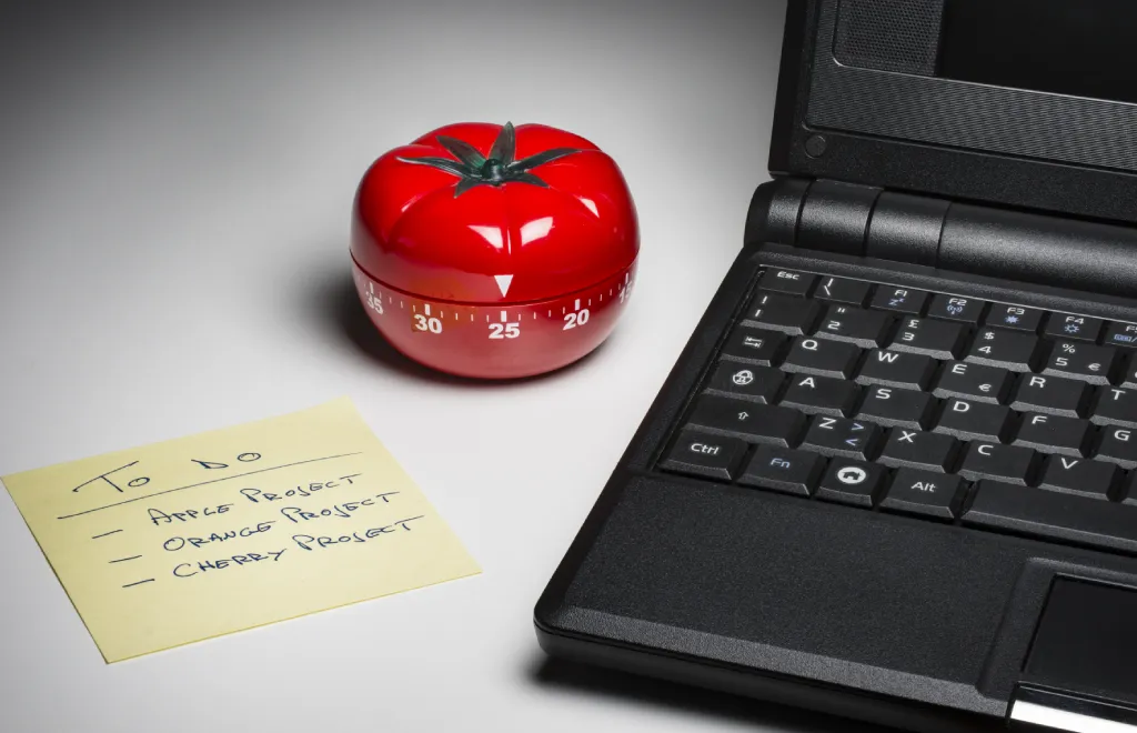 En tomat og en bærbar datamaskin for å utføre Pomodoro-teknikken for tidsstyring